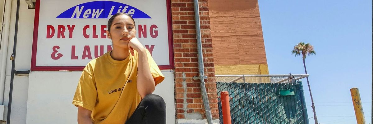 photograph of a Latina woman in front of the facade of a laundromat in the U.S.