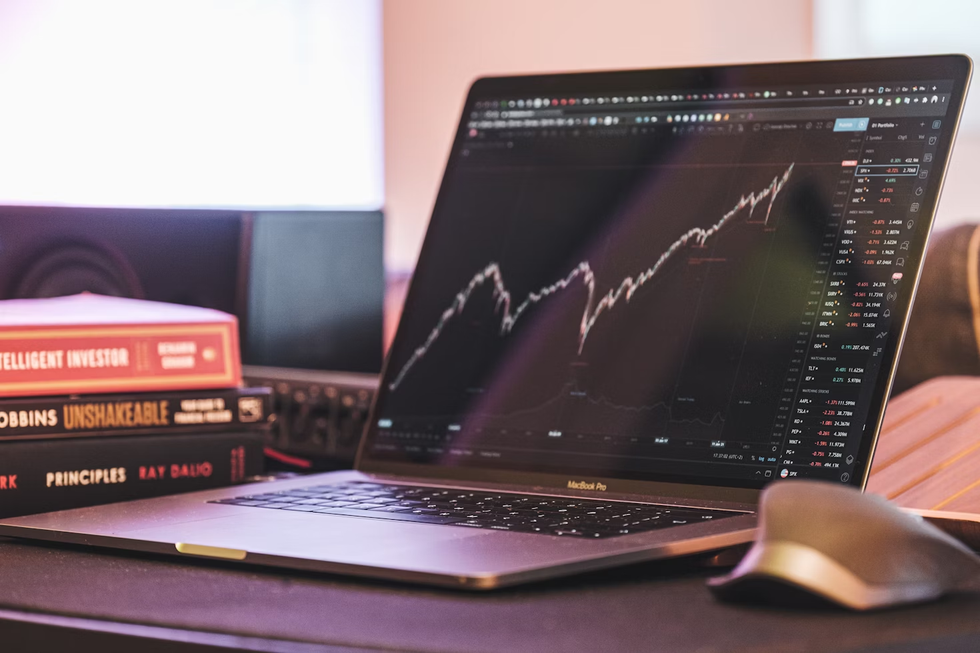 a photo of a laptop on a desk showing a graph of a rising stock