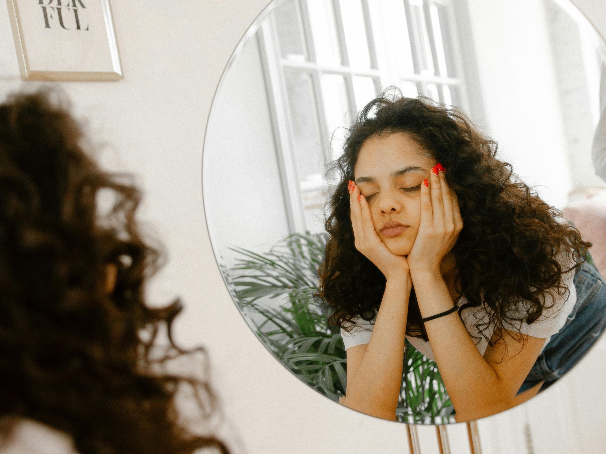 young woman facing her reflection in a mirror
