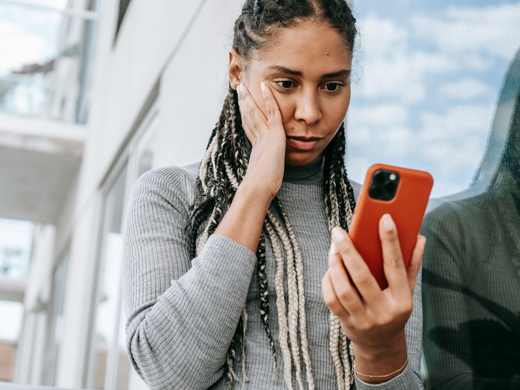 young woman looking at her phone with worried expression
