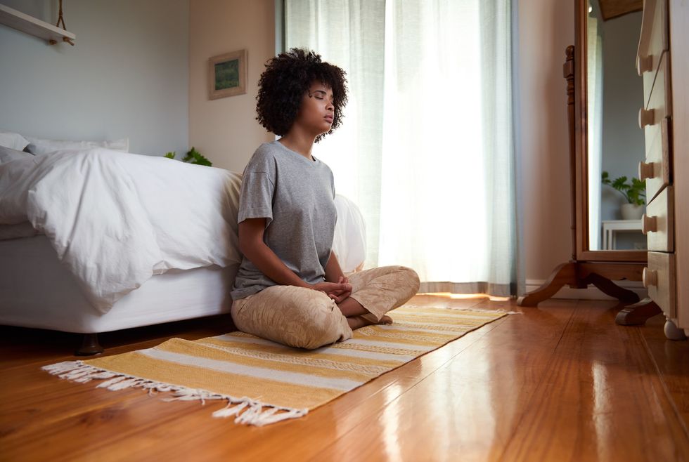 Meditating-woman-sitting-on-the-floor-in-her-room