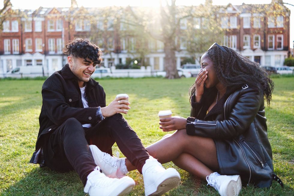 Couple-laughing-in-the-grass-drinking-coffee-in-the-park