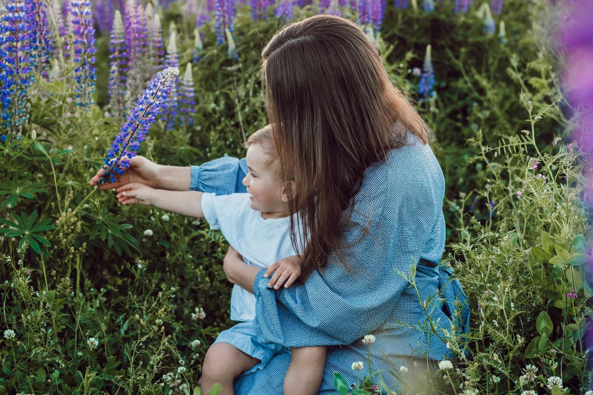 woman sitting with baby on her lap surrounded with purples flower