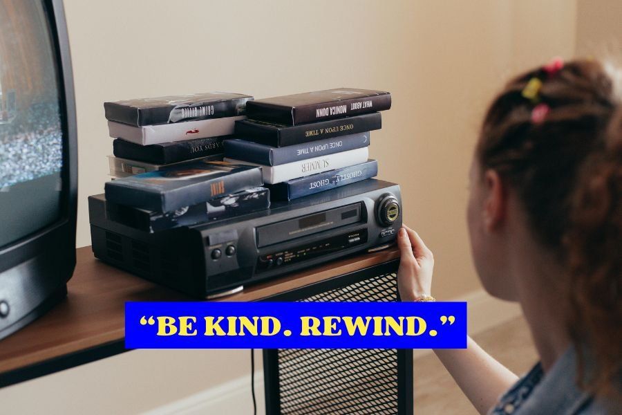vcr with vhs tapes piled on top of it 