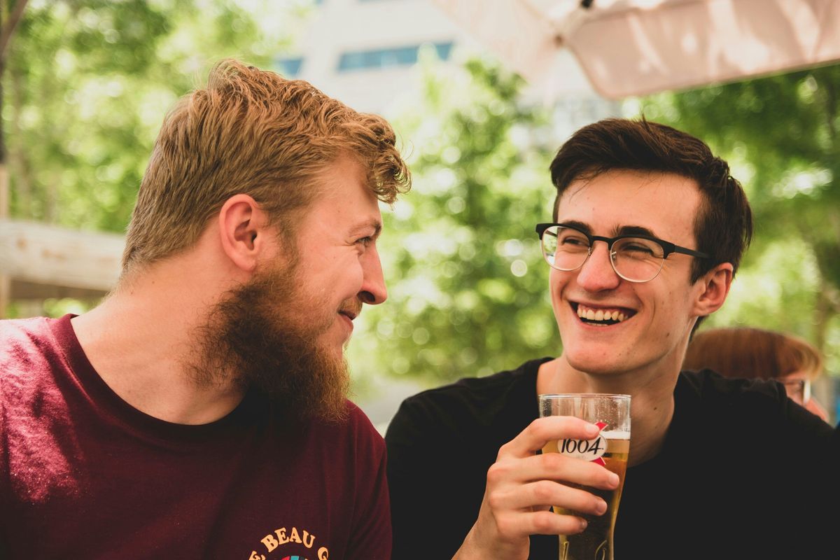 two men talking, drinking beer