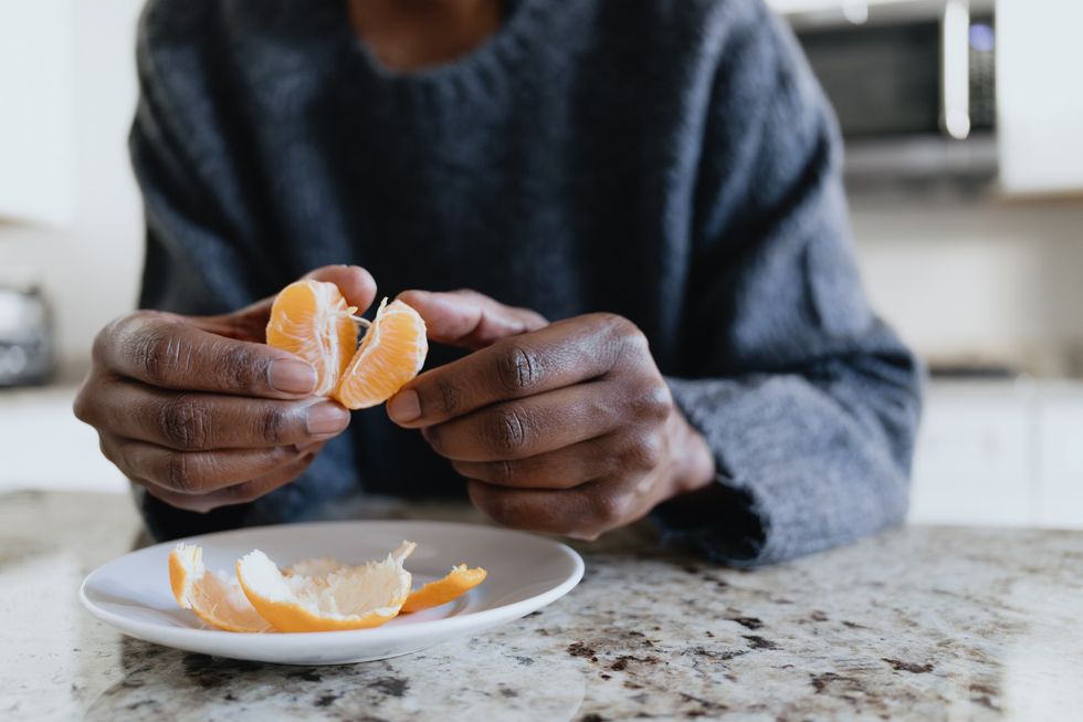 Close-up-of-a-faceless-Black-woman-peeling-a-clementine