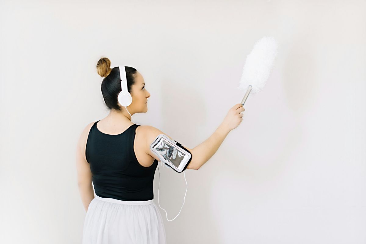 woman wearing headphones and carrying a duster