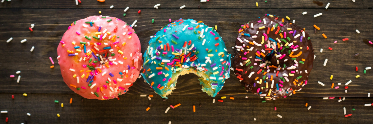 photograph displaying three donuts, each topped with uniquely colored glazes.