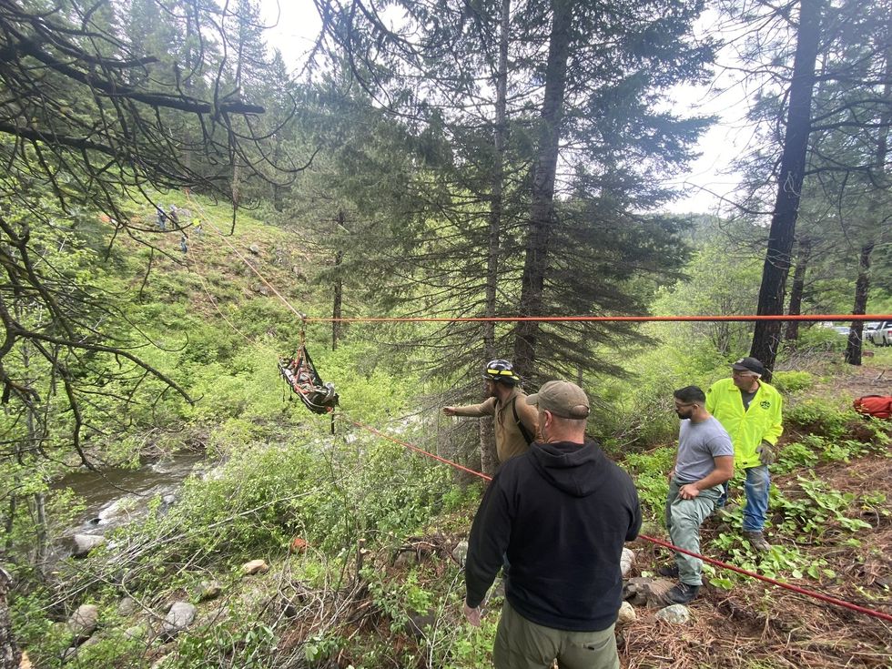 man being pulled in a rescue basket on ropes across a ravine