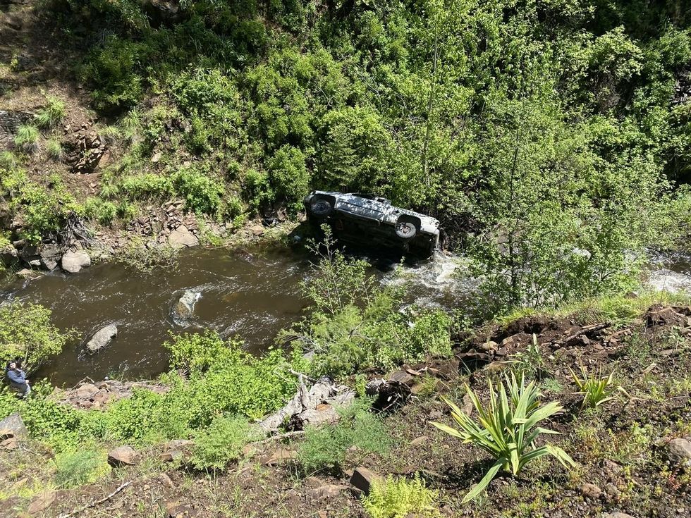 white pickup truck on its side in a creek