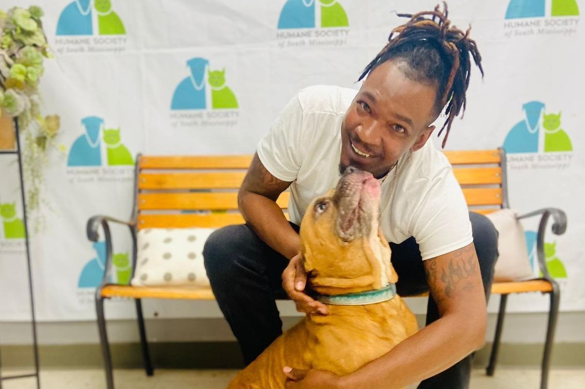 Man smiles while holding dog
