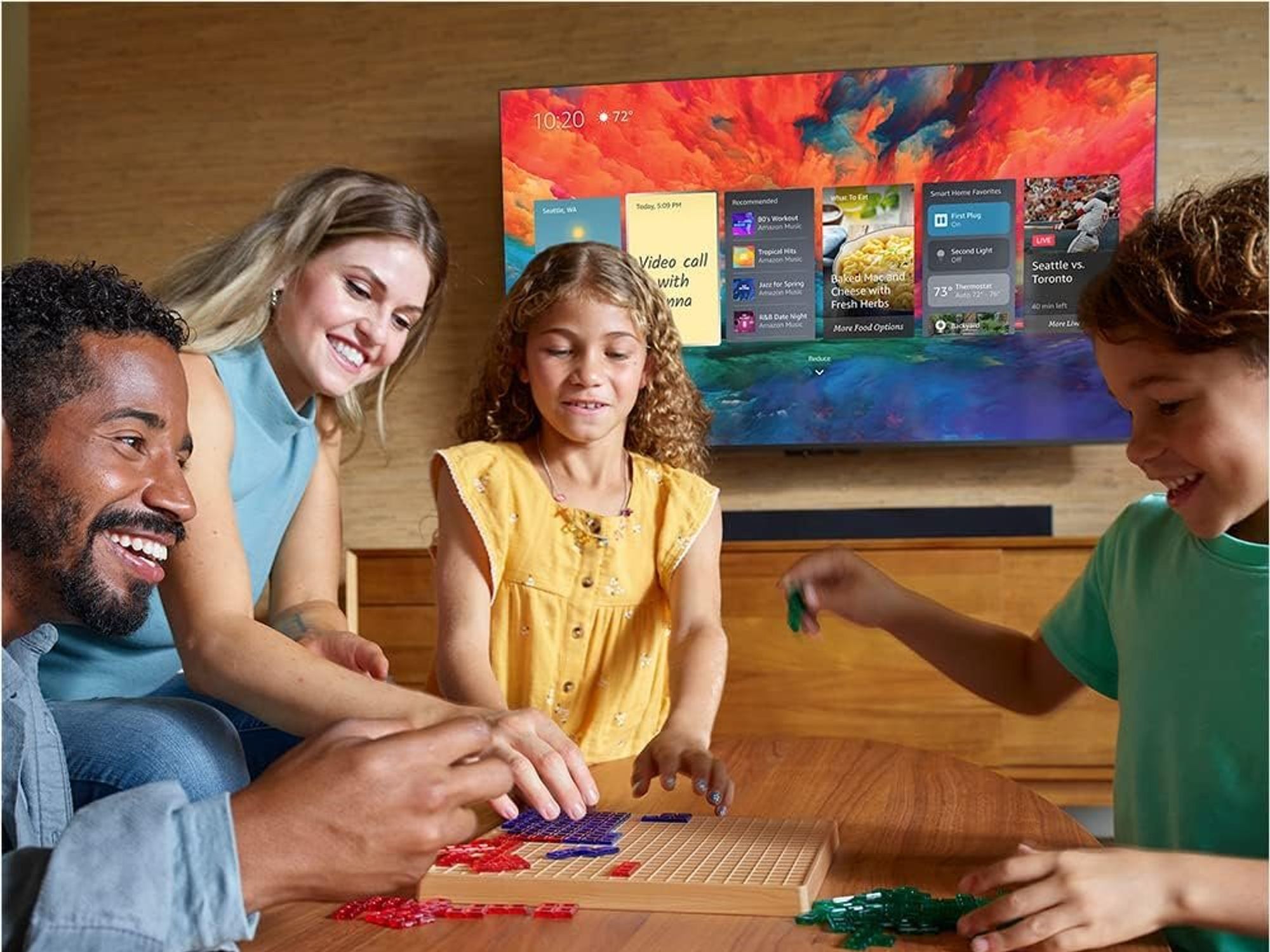 a photo of a family playing games and the Amazon Fire TV Omni Series 4K UHD Smart TV on the wall in the background.