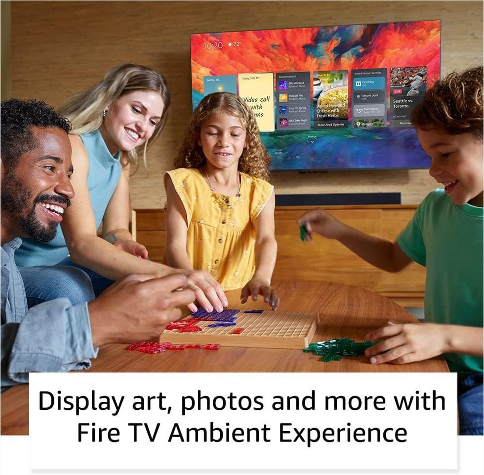 a photo of a family playing games and the Amazon Fire TV Omni Series 4K UHD Smart TV on the wall in the background.