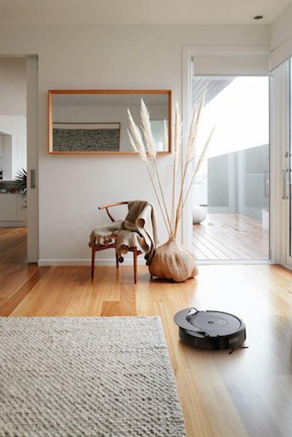 a photo of iRobot's Roomba Combo 10 Max Robot + AutoWash Dock vacuuming the floor next to a carpet