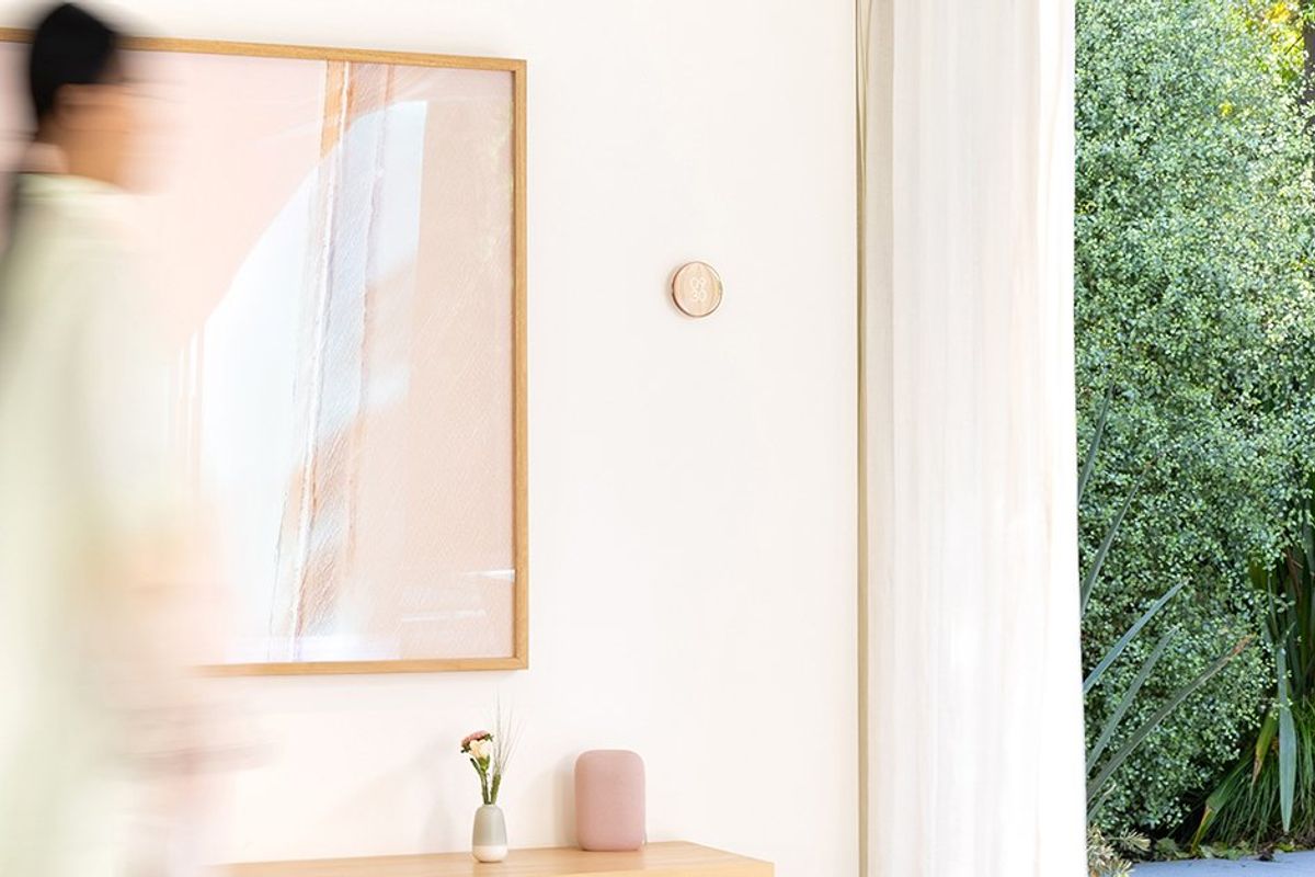 a photo of a woman walking infront of new Nest Learning Thermostat which reacts to her movements