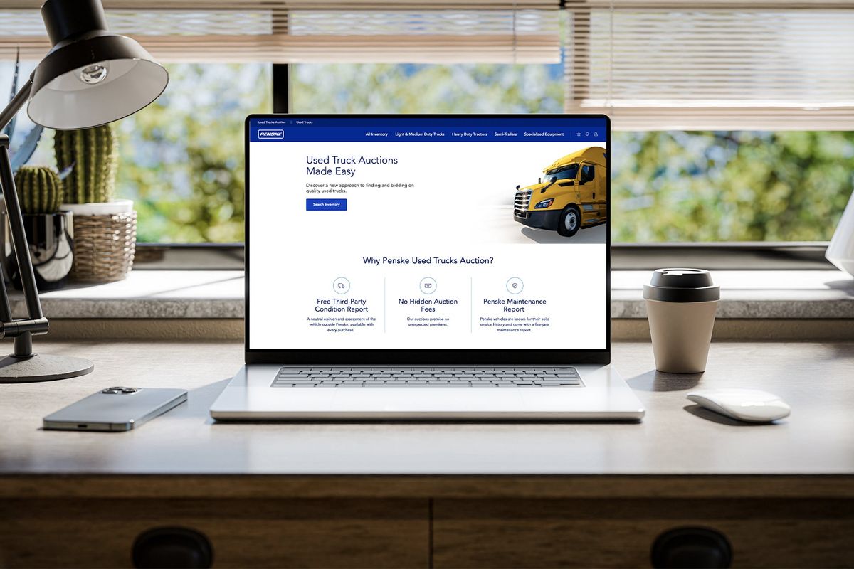 Laptop displaying Penske Used Truck Auction website on a desk.
