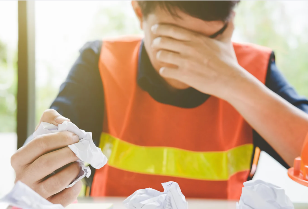 child with their head in their hand crumpling a paper in frustration