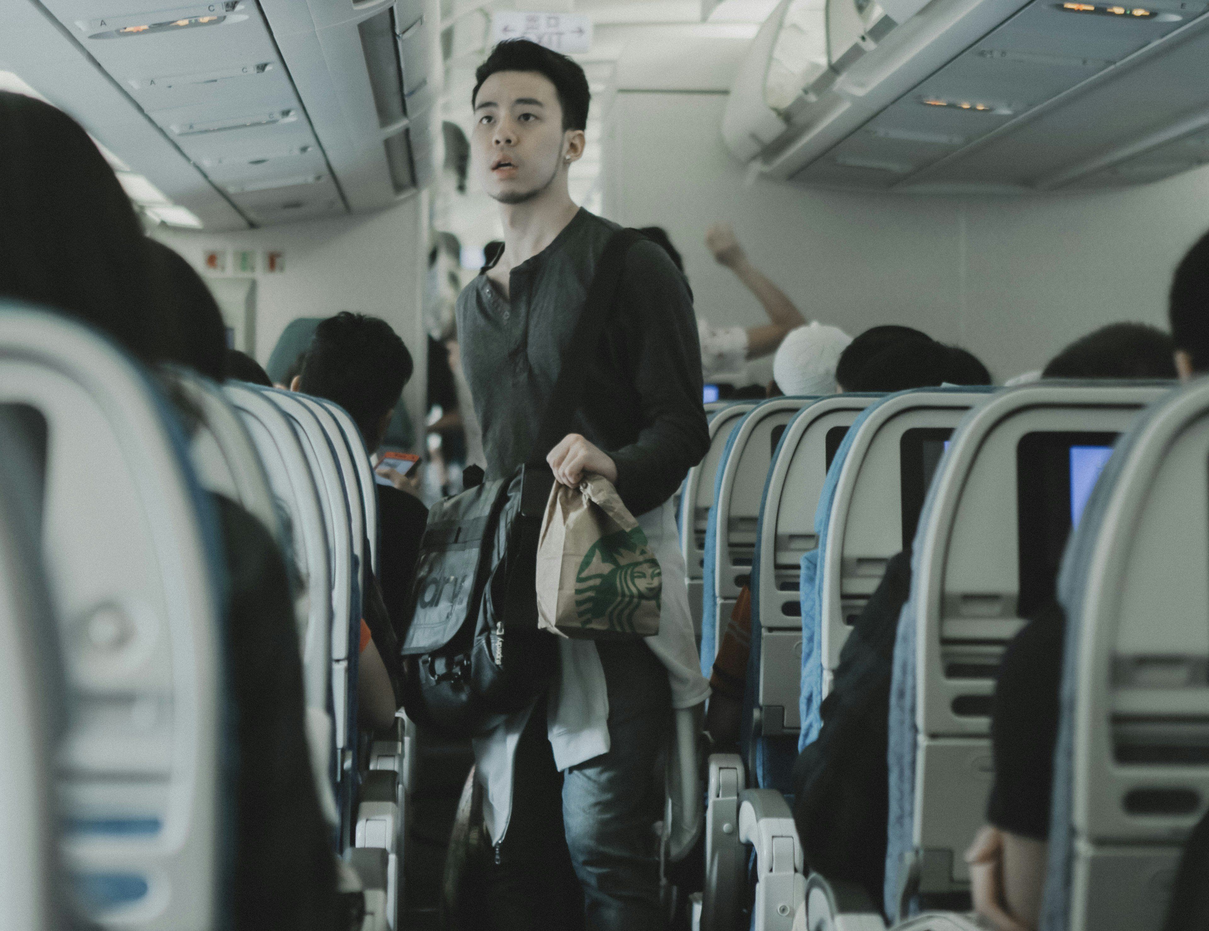 Man walks to his seat on an airplane