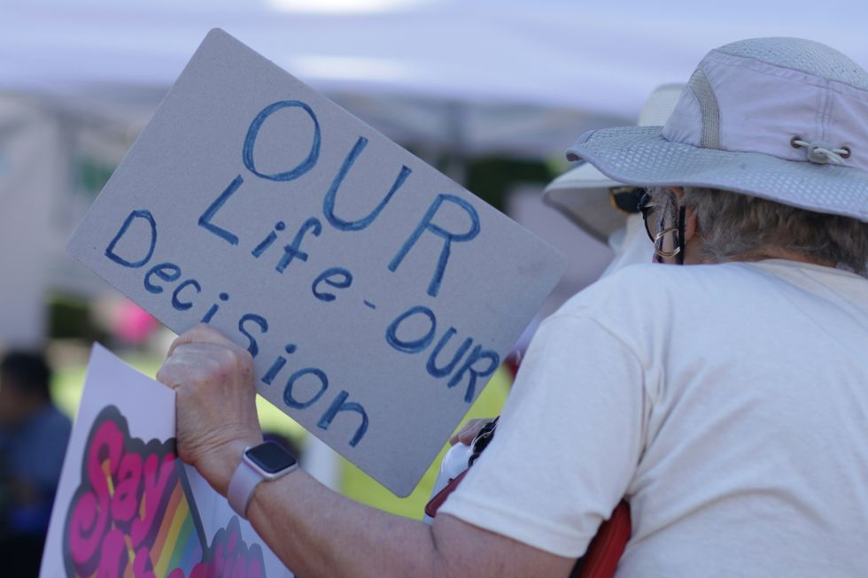 a man holds a sign for pro-choice arguments reading "our life - our decision"