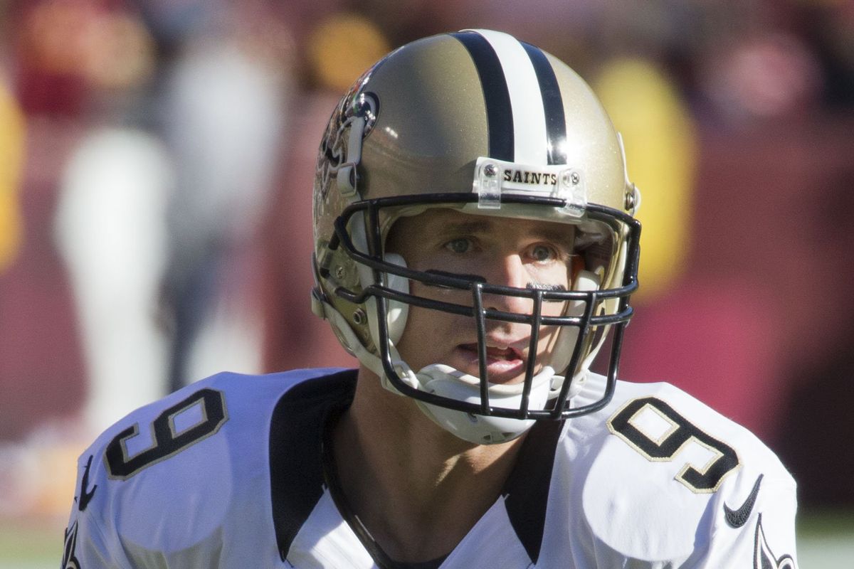 Drew Brees holds a football in his New Orleans Saints uniform