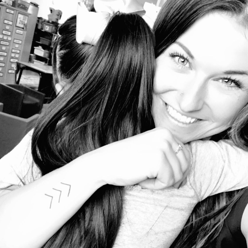 Woman hugging her child while displaying a three arrow tattoo