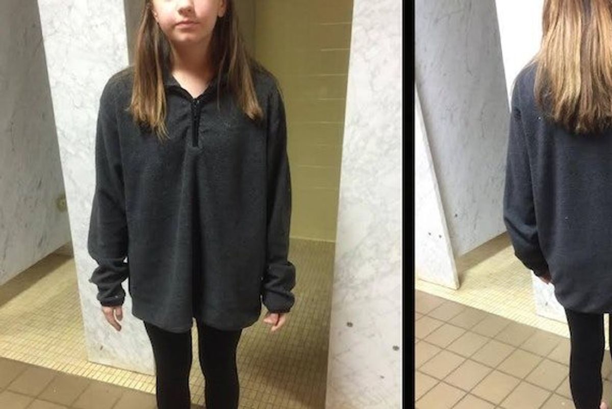 A girl standing at school wearing a baggy shirt and leggings