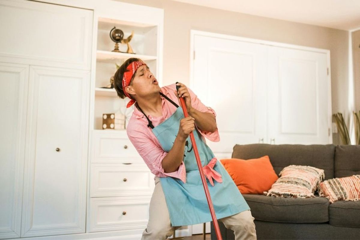 person singing into mop handle
