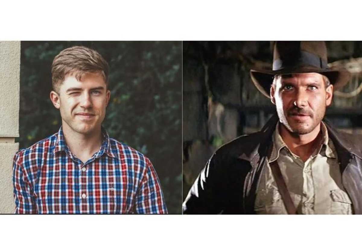 A man smarks next to a photo of Indiana Jones