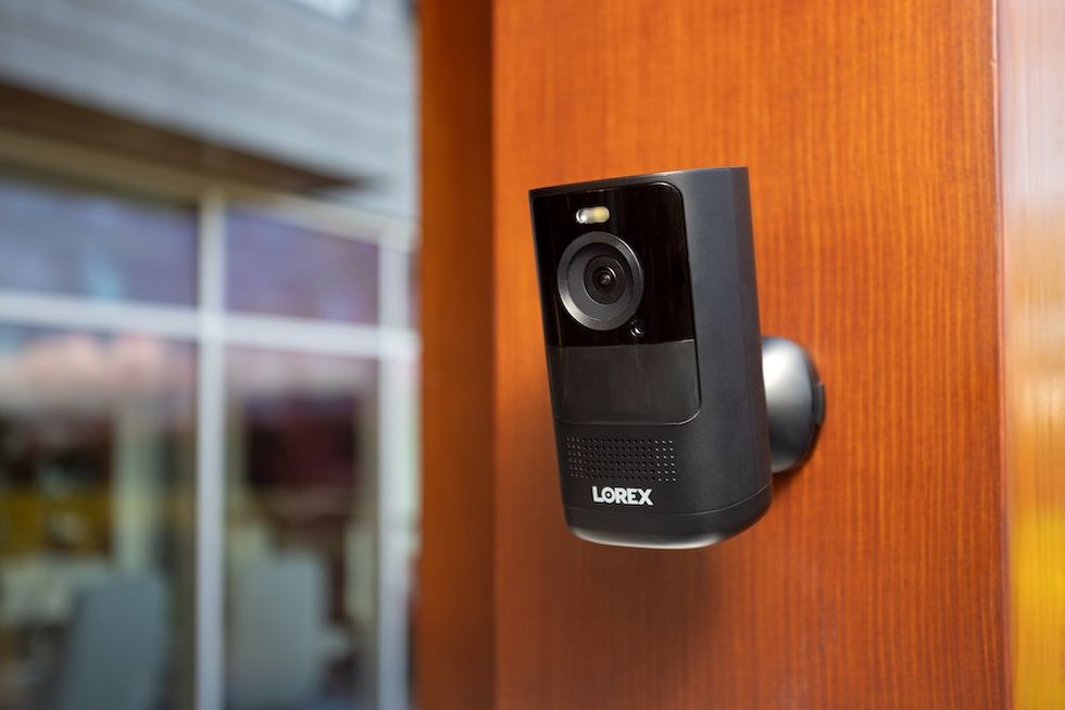 a photo of a black Lorex 4K Spotlight Battery Camera on a wall.