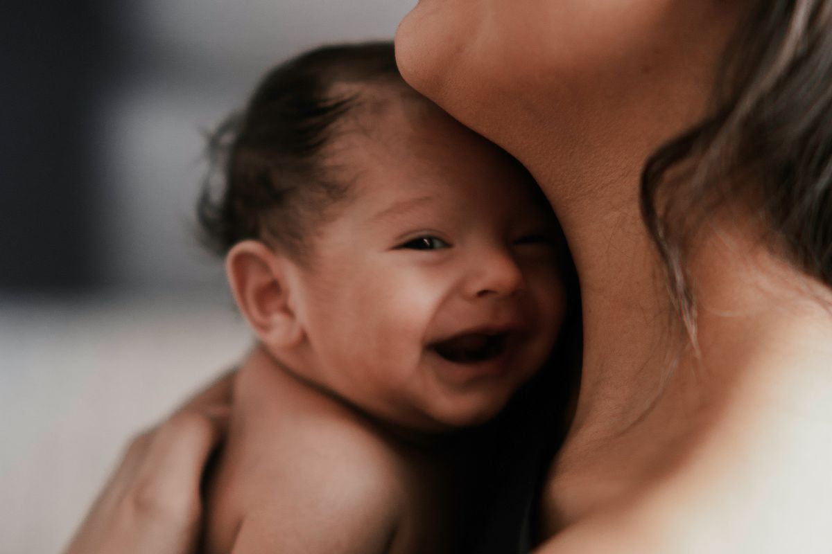 woman carrying smiling baby