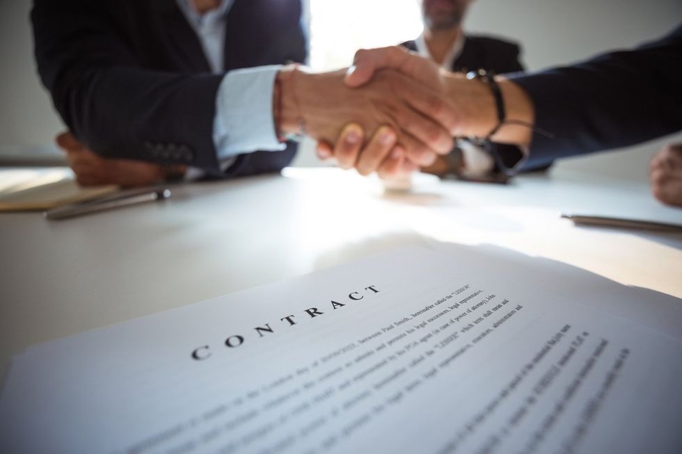 a photo of Businessmen shaking hands over contract