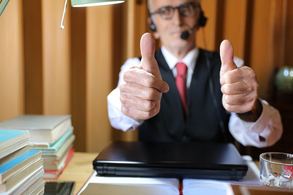 a photo of An elderly man in his office showing thumbs