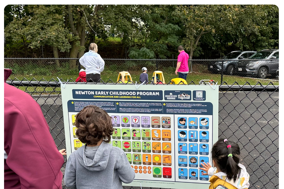 kids at a playground in front of a communication board