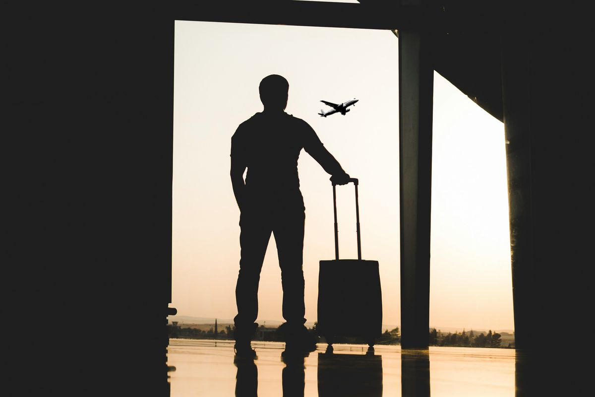 silhouette of a man holding luggage inside airport