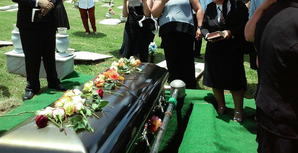 casket in a cemetery with people standing around it