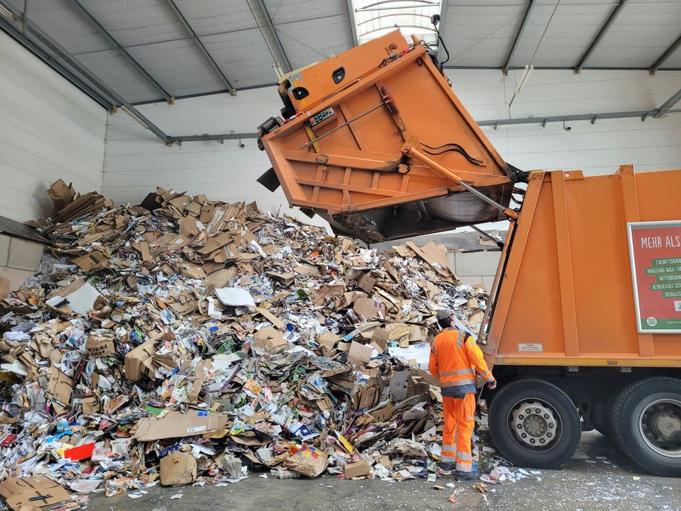 a garbage man standing next to a pile of trash