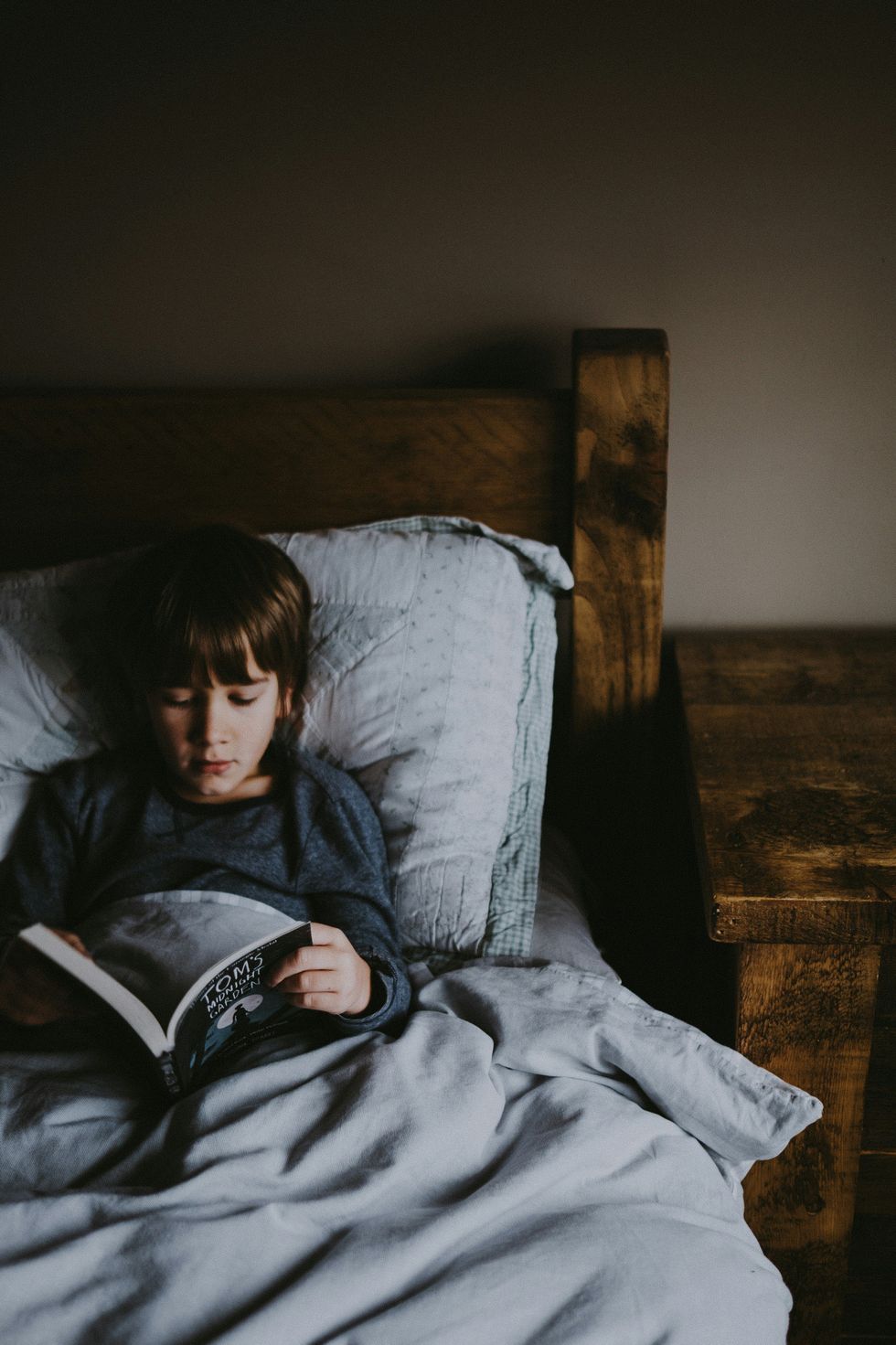 boy reading a book on bed