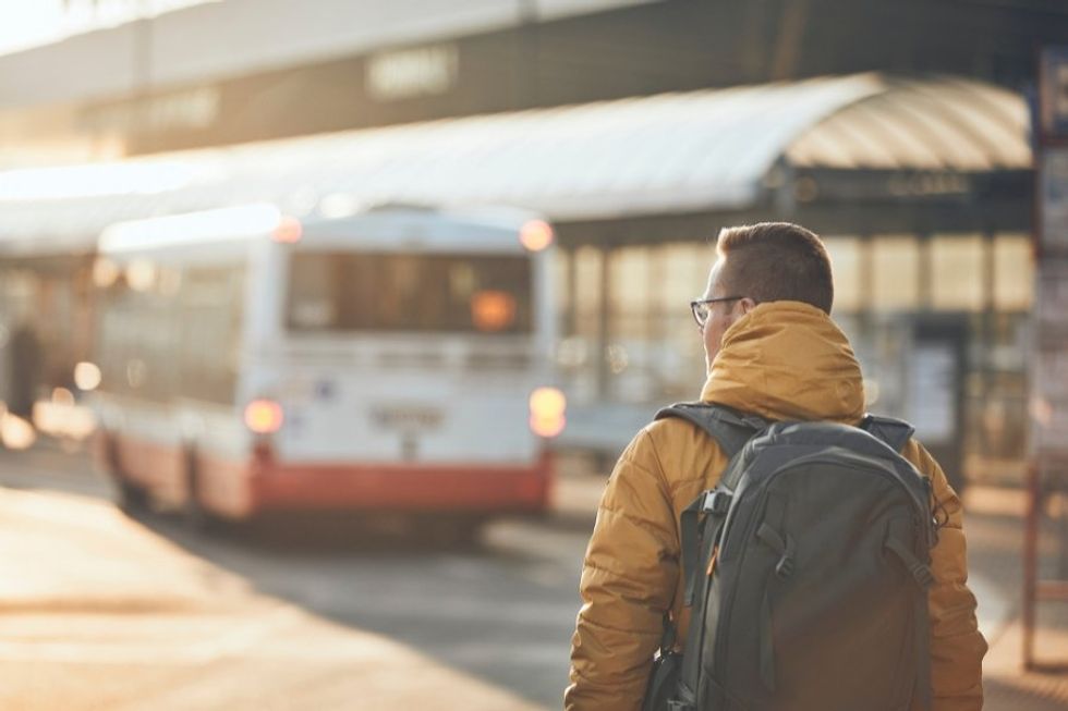 man walking alone behind a bus