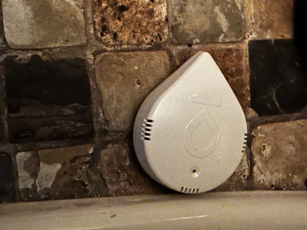 a photo of the Moen Smart Leak Detector on the floor next to a toilet