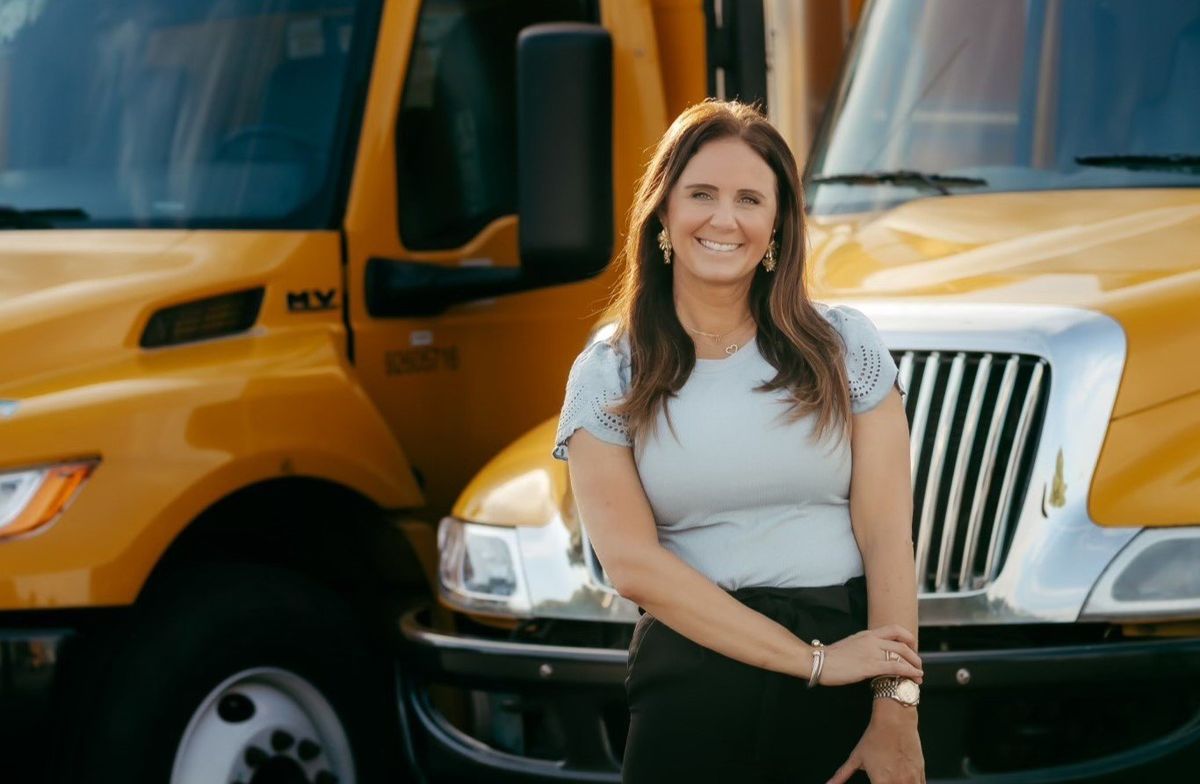 Photo of woman standing in front of yellow trucks