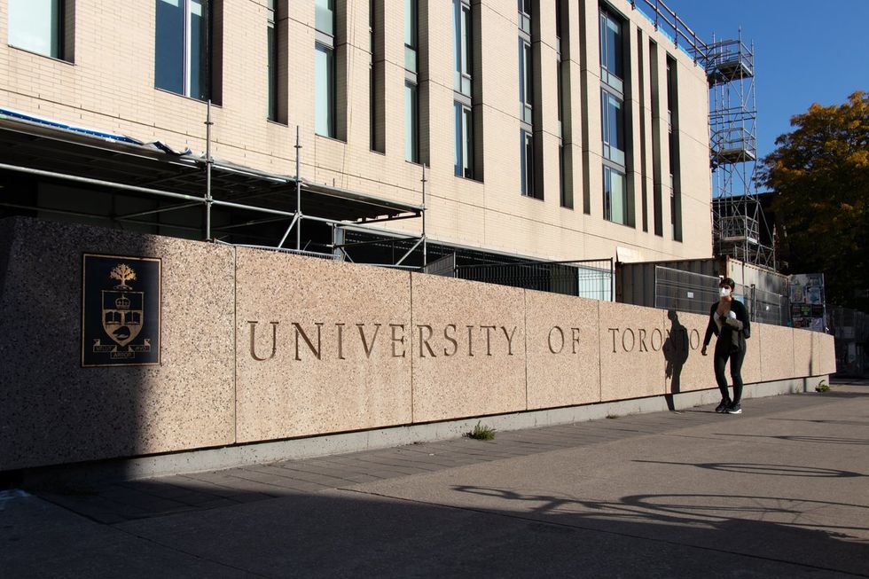 A student passing by a sign out front of the University of Toronto. stock photo