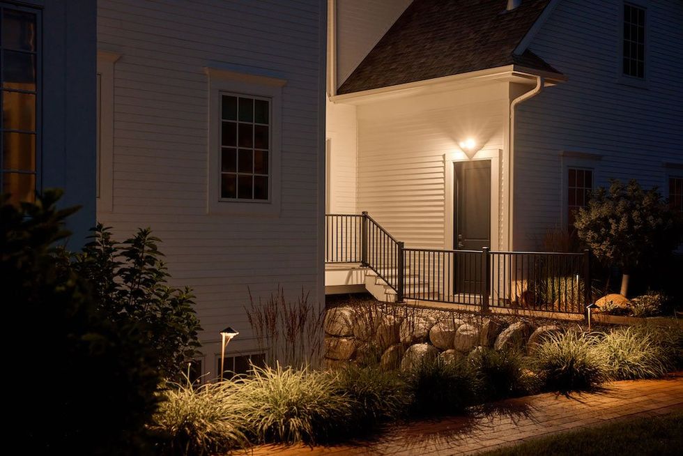 a photo of Arlo Wired Floodlight Camera above a backdoor of a house at night.