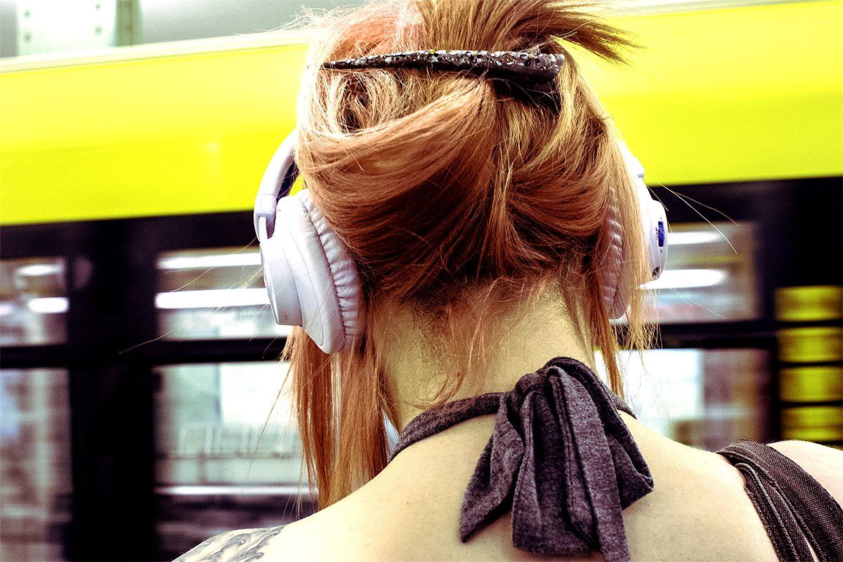 A young woman listens to her headphones in the subway.