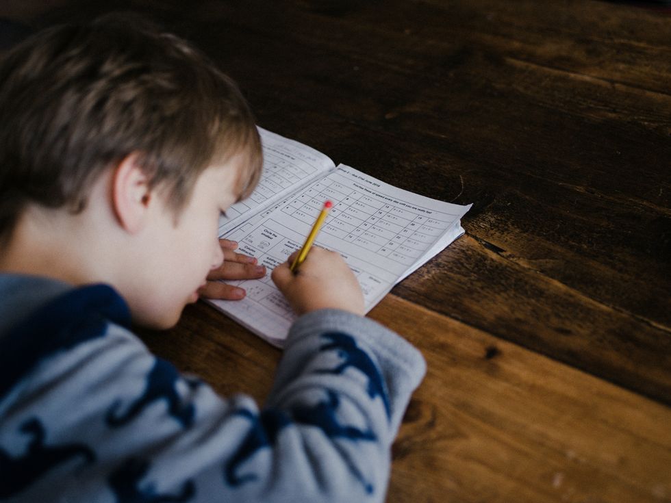 un garçon fait ses devoirs au bureau en bois