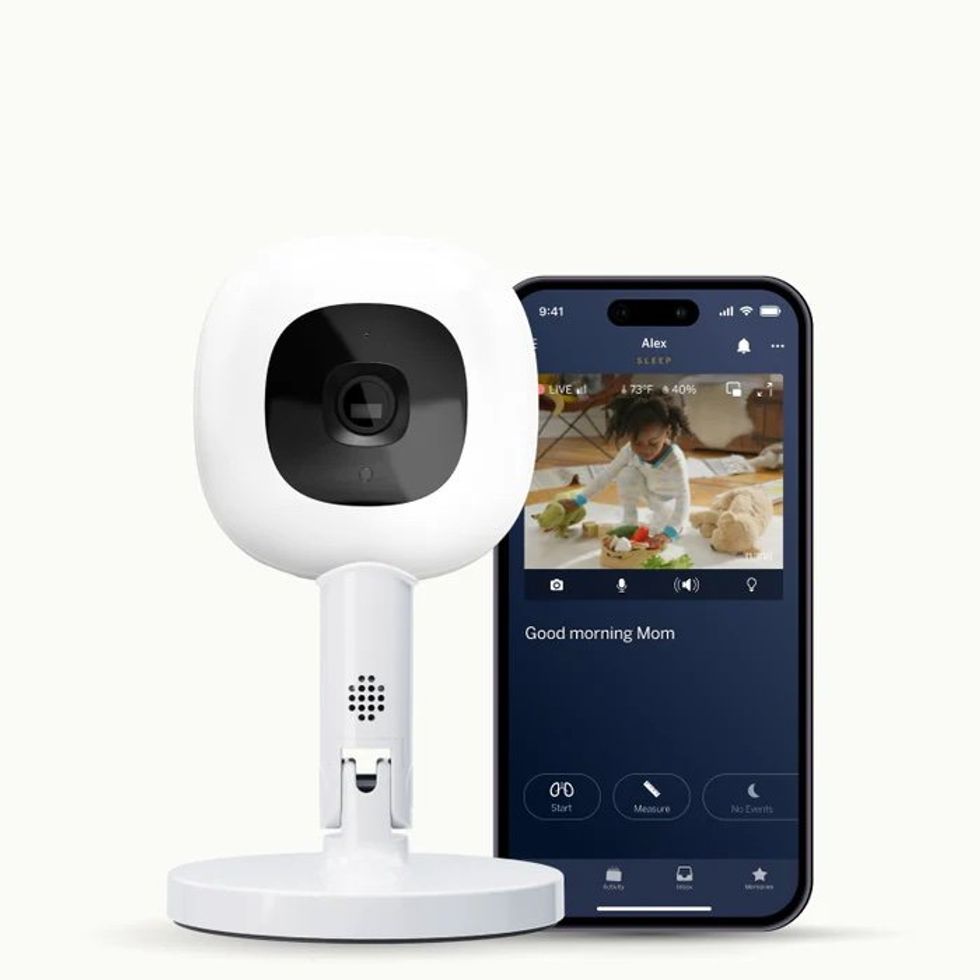 a photo of Nanit Pro Monitor with smartphone showing the app