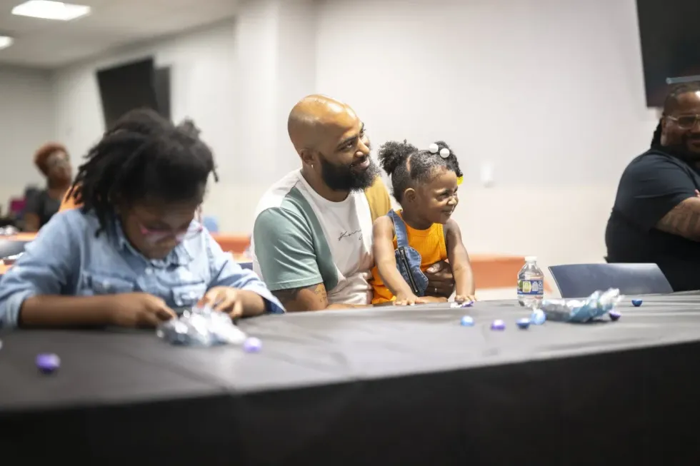 A man with his daughters sits at a table listening to doula training
