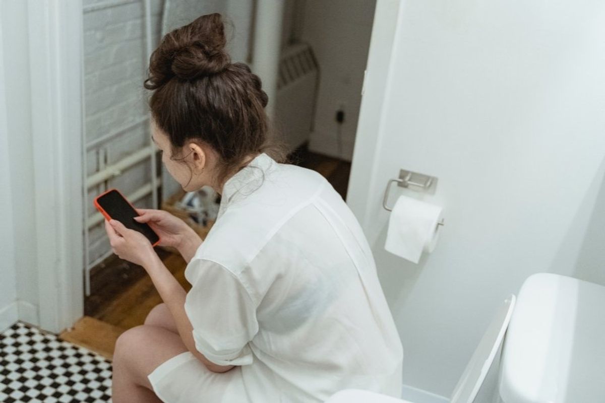 woman using phone on the toilet