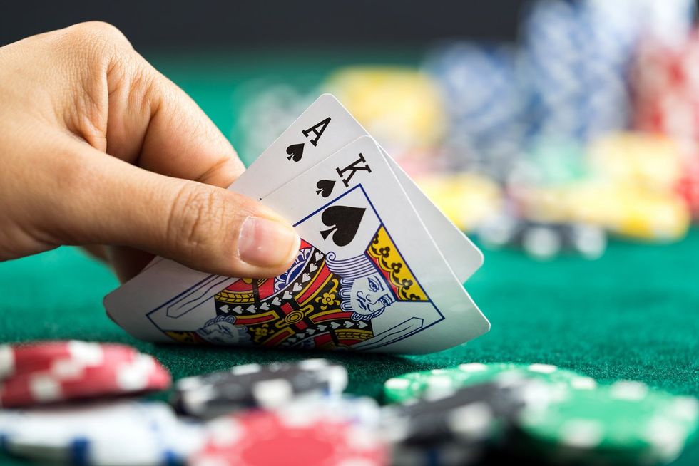 Gambling Hand Holding Poker Cards and Money Coins Chips stock photo