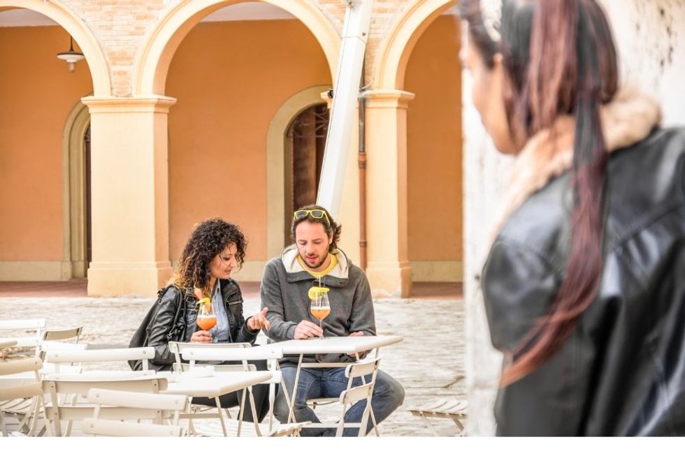 woman peering at a couple from behind a pillar