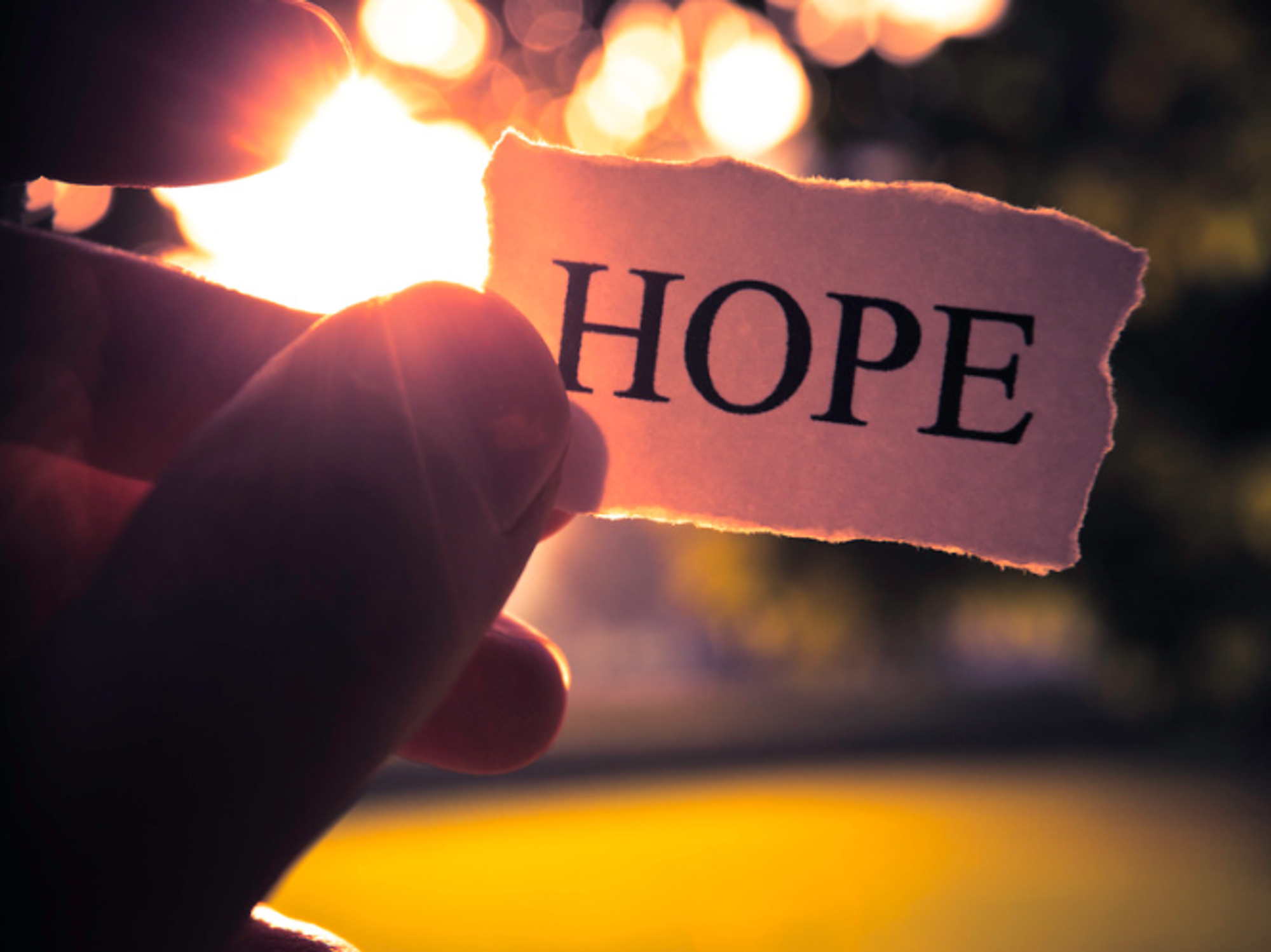 A hand holding a note that says "hope"